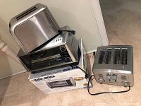 Photo showing two toasters and one Black & Decker toaster oven stacked, with toaster oven box visible.