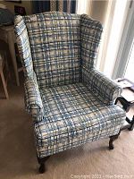 Front view of plaid wingback chair showing rolled arms and high back