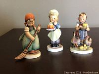 Photo showing all three Goebel ceramic dolls: girl sweeping, boy chef, girl feeding ducks.