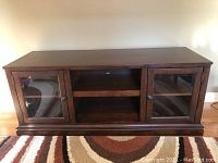Front view of the wood TV stand showing two glass door cabinets and two open shelves in the center
