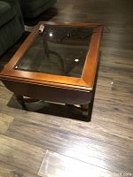 Photo of rectangular wooden coffee table with glass top, partially folded.