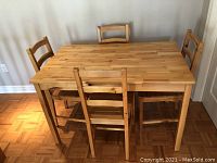 Full view of the wood dining table with four chairs around it showing overall condition and design.