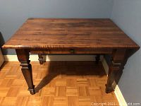 Front view of the wood desk/table showing the smooth wood surface and carved legs.
