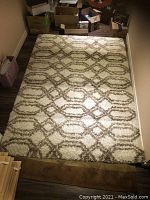 Full view of the rectangular area rug with beige and taupe geometric oval designs on cream background, showing size and condition in room setting.