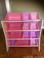 Front view of the toy organizer with all twelve pink storage bins inserted into the shelves.