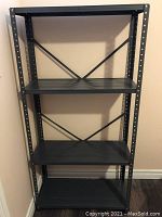 Black metal rack with flat shelves against wall