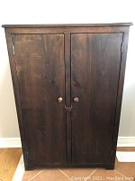 Front view of the solid wood two-door cupboard with round knob handles.