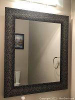 Front view of the rectangular wall mirror showing the detailed dotted pattern on the metal frame and the clean reflective glass surface.