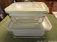 Stacked large and medium glass food storage containers with lids on a table