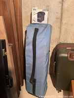 Blue carrying bag with black strap, standing upright with boxed Intex electric pump placed on top.