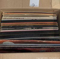 Top view of a box filled with multiple vinyl record albums showing the edges and spines.