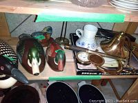 Wooden decoys and brass accessories on shelf