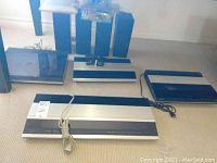 Three silver front-panel components on carpeted floor in front of four black speakers and clear plastic cover on top of speaker