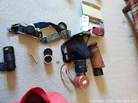 Canon AE1 film camera, lenses, lens cases, and Canon PowerShot SD-870 IS digital camera laid out on carpeted floor.