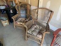Pair of natural wicker chairs with floral cushions, one standard and one rocker, shown side by side in a garage