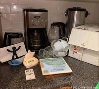 Full lot displayed on countertop showing coffee maker, kettle, coffee urn, cups, saucers, mugs, and accessories