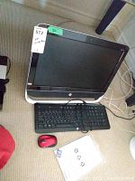 HP Pavilion all-in-one computer with 20-inch screen next to wired keyboard, red mouse, and manuals