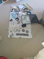 Photo showing entire assortment of costume jewelry laid out on a white cloth on carpet, including necklaces, bracelets, earrings and rings.