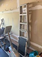 5-step aluminum ladder leaning against garage wall.