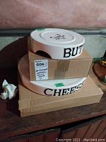 Stacked butter and cheese platters showing side text and tops, with labels for identification