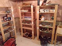 Three wood shelving units in basement setting, with various items on shelves not included in sale.