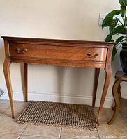 Front view showing single center drawer with metal bail handles and carved front apron.