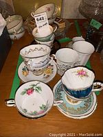 Photo showing assorted tea cups and saucers including floral and gold design patterns.