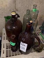 Various glass bottles and brown jugs grouped together on shelving