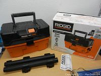 Ridgid Pro Pack wet/dry vacuum in orange and black with box and accessories on table.