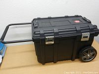 Side view of black Husky job box showing telescoping handle and one large wheel.