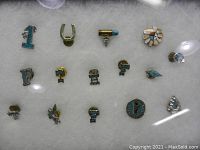 Full lot of assorted turquoise pins displayed on a white padding background, showing all 15 pins of various shapes and colors including #1, horseshoe, bullet, flower, letters, and geometric shapes.