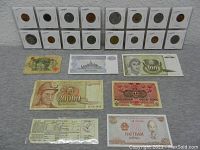Full view of foreign coins in holders and banknotes arranged on a flat surface