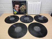Photo of The Elvis Presley Story box set cover, five vinyl records, and a printed insert against a white background.