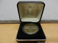 Front photo of the coin inside the protective case showing the coin's design and engraving.