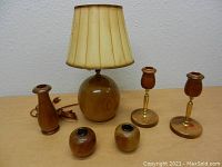 Full set photo showing one table lamp, three candlesticks, and two small myrtlewood holders on a flat surface.