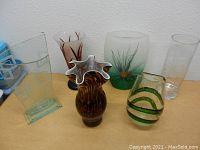 Six assorted decorative glass vases on table showing variety in style and color.