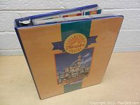 Photo showing binder upright displaying front cover with Disneyland Sleeping Beauty Castle illustration and 40th Anniversary logo.