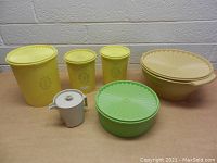 Photo of seven vintage Tupperware containers including yellow nesting bowls, yellow and green containers, and small white ceramic pot.