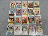 Top-down view of all 20 Garbage Pail Kids cards arranged in four rows of five on a gray background, showing visible character names and colorful artwork.