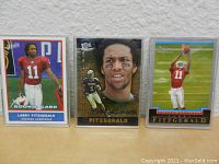 Front view of three 2004 Larry Fitzgerald rookie football cards in clear protective cases arranged side by side.