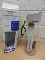 Photo of LifeStraw Water Filter Bottle with original box, showing bottle, filter inside, lid, and attached carabiner.
