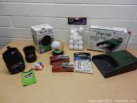 Full assortment of golf practice items including pop-up putting cup, water globe challenge, golf dice, golf balls, tees, and accessories