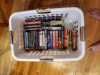 Top view of laundry basket filled with over 35 young adult books of various series and colors, stacked and lying flat.
