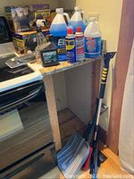 Photo of windshield washer fluids, WD-40 can, motor oil bottle, spray bottle, and back seat organizers on a shelf