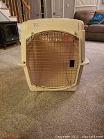 Front view of the Petmate XL dog kennel showing clay color plastic shell and chrome wire door with latch.