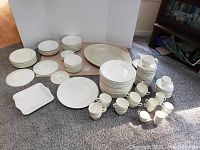 Group shot of all dishes including stacks of plates, bowls, cups, saucers, platter and gravy boat arranged on floor.