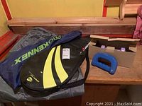 Multiple racket covers from Prokennex and Wilson next to purple and blue hand weights for exercise.