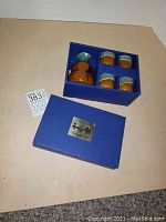 Blue box holding one ceramic sake bottle and four matching sake cups with brown and blue glaze in new condition