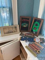 Overview of all items including three framed arts and multiple wood signs placed on a bench and floor by window.