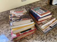 Two stacks of vintage cookbooks arranged on a countertop showing spines and covers.